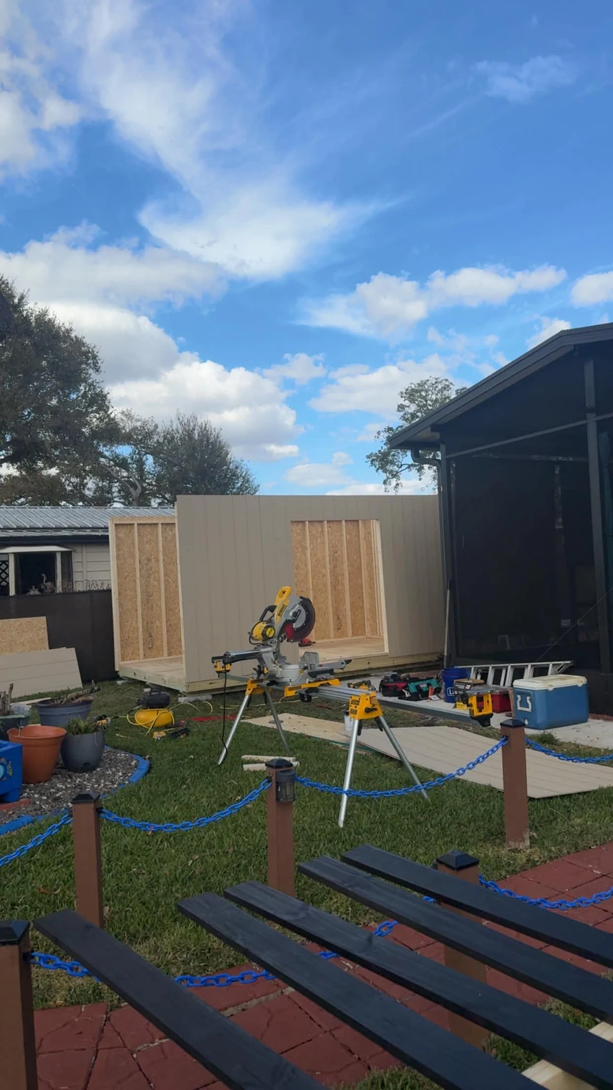 Exterior view of the 10 by 16-foot Patriot shed showing wall panels around a wide framed entry opening beside the patio