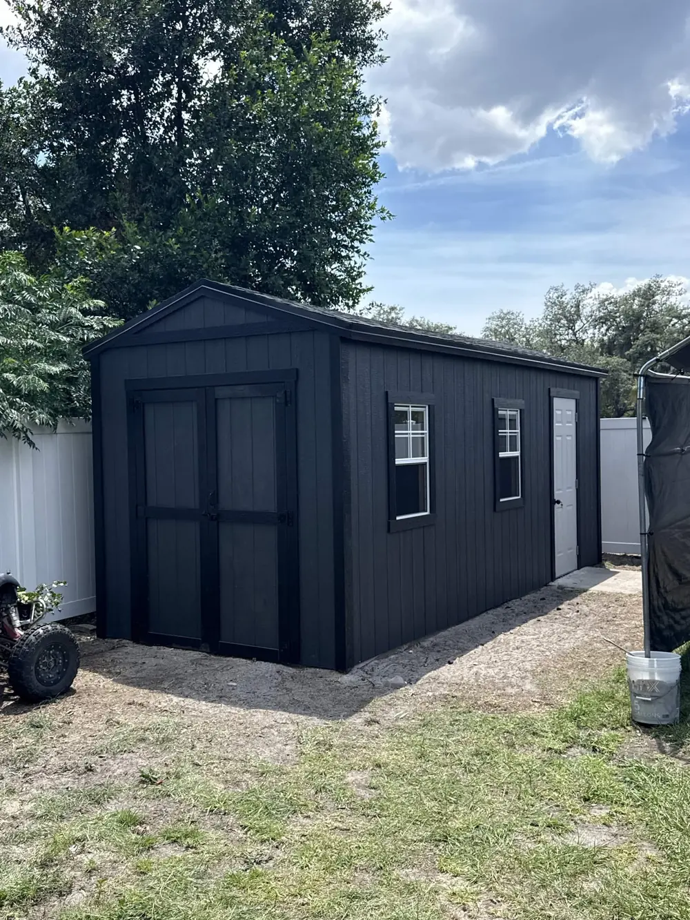 Large charcoal custom workshop shed built in a wooded yard