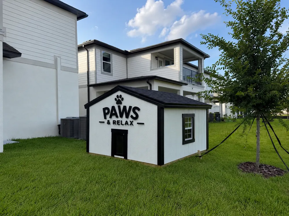 Small black and white custom shed built beside a fenced home
