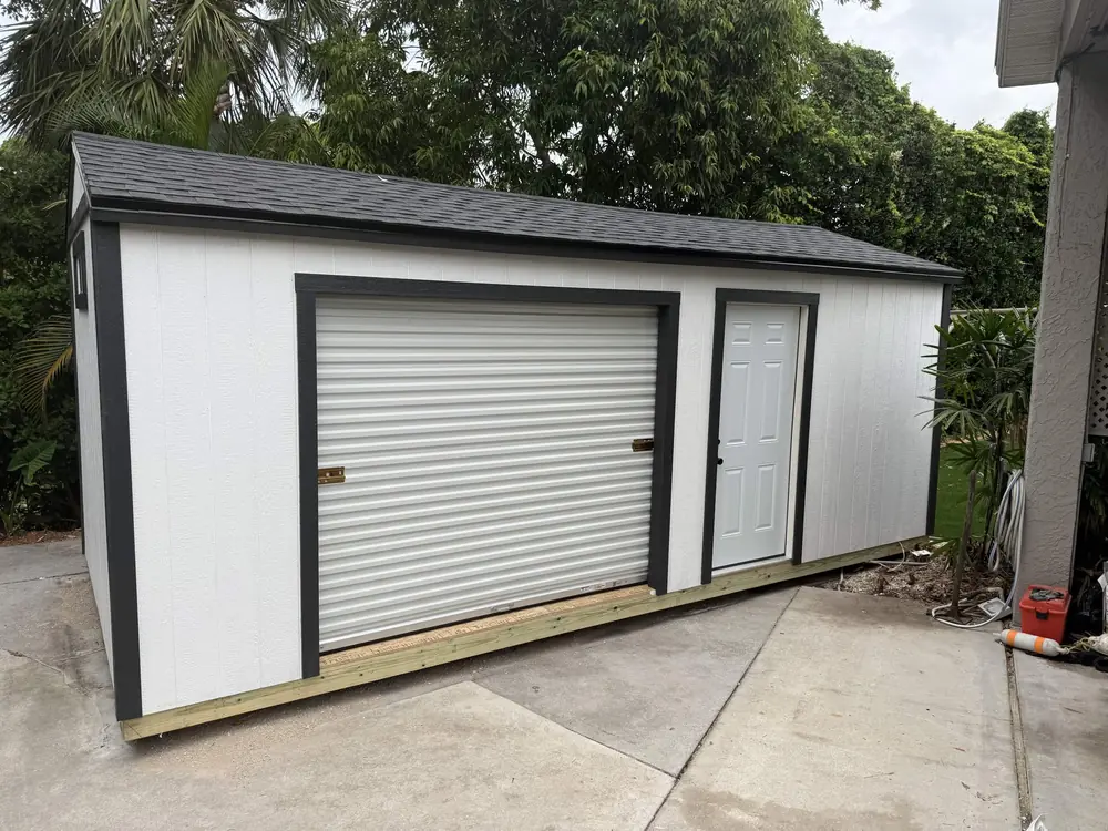 Black and white custom shed with a roll-up workshop door