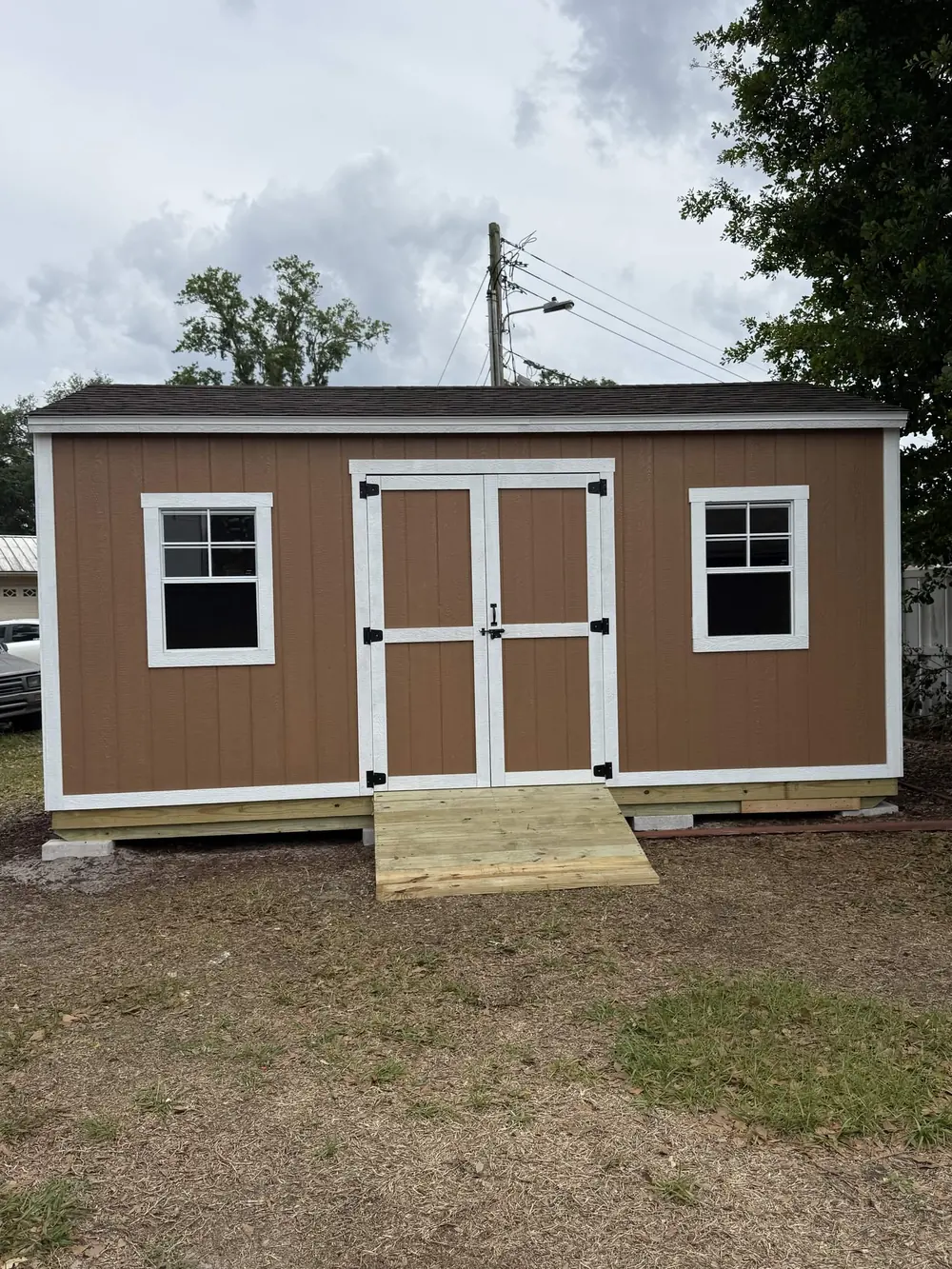 Wide tan custom shed with double doors and two windows